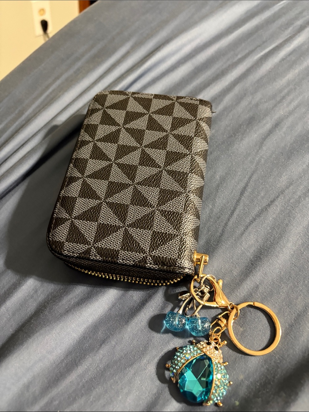 Blue Crystal Beetle Keychain with blue Cherry Charms on black geometric wallet.